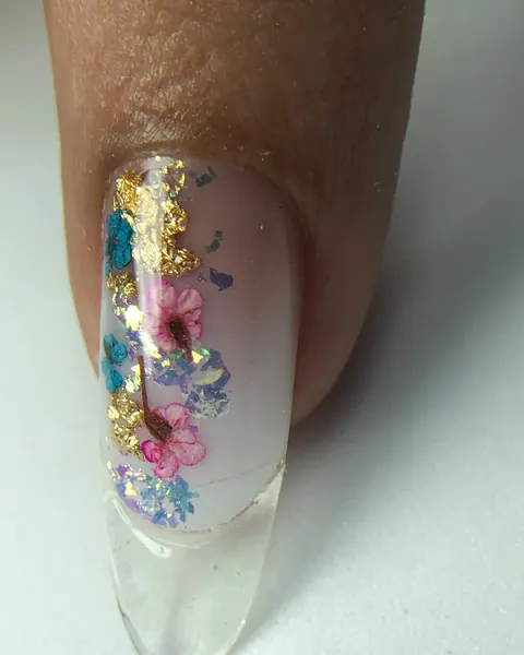 Unha encapsulada com flores secas e folha dourada