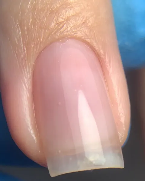Unha quadrada em gel transparente rosado feita com molde duplo, em close